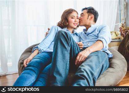 Asian couple having kissing romance on sofa in living room domestic house in Valentines day. Lifestyle and happiness family concept.