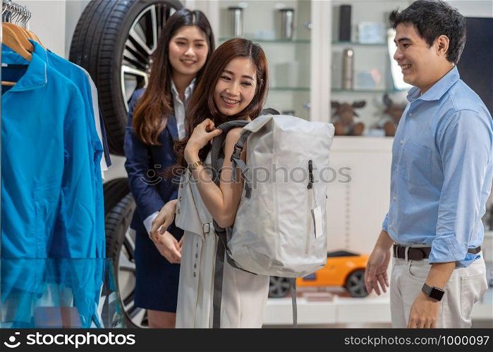 Asian couple holding and using bag in car showroom,