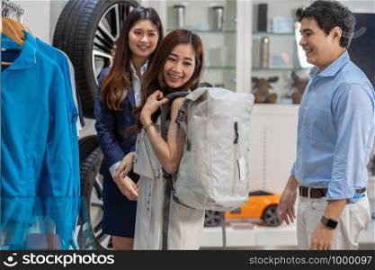 Asian couple holding and using bag in car showroom,