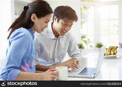 Asian Couple Looking at Laptop In Kitchen
