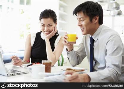 Asian Couple Looking at Laptop Over Breakfast