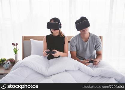Asian couple lover Enjoying Playing Videogame at bed room, Asia couple lover feeling happy fun and virtual reality, VR playing games together while lying in bed room at home concept.