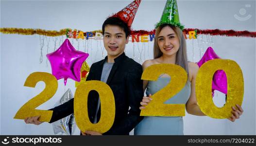 Asian couple lover holding 2020 numbers celebrating a new year at a bar shouting and laughing and Counting down to midnight on a new year party