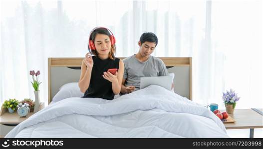 Asian couple lovers listening to music and singing on his bed and happy on relax time
