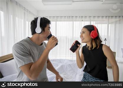 Asian couple lovers listening to music and singing on his bed room and happy on relax time