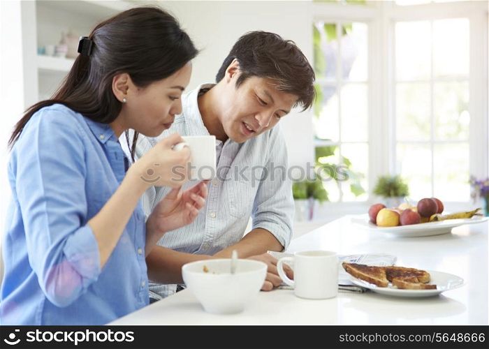 Asian Couple Reading Newspaper At Breakfast