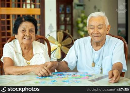 Asian couple senior playing with a jigsaw puzzle at home