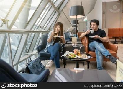 Asian couple sitting and eatting inn airport lounge when waiting the flight at modern international airport, travel and transportation concept