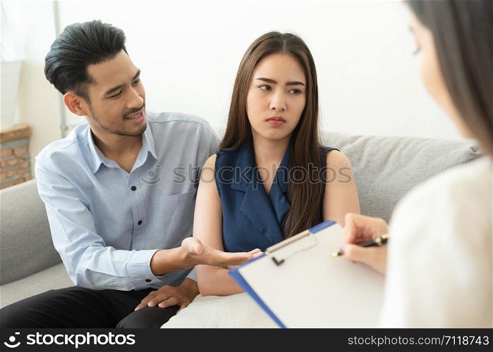 Asian couple sitting on the couch in the psychiatrist room to consult mental health problems by doctor, Health and illness concepts