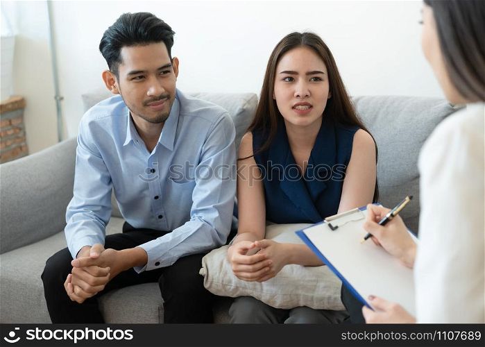 Asian couple sitting on the couch in the room to consult mental health problems by doctor, Health and illness concepts