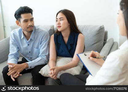 Asian couple sitting on the couch in the room to consult mental health problems by doctor, Health and illness concepts