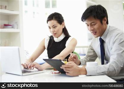 Asian Couple Using Digital Devices At Breakfast Table