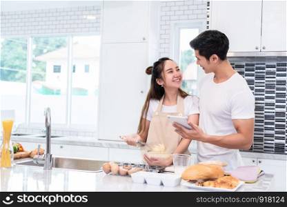 Asian couples cooking and baking cake together in kitchen room at home. Love and happiness concept Sweet honeymoon and Valentine day theme