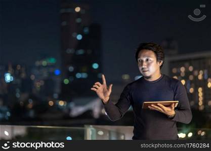 Asian creative freelancer using technology tablet with smile action in the financial district area at bangkok river side, Thailand, Business technology with career concept