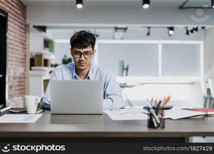 Asian creative man drawing work plan on paper board. Young professional business male think and write information reminder on paper on brick, business situation, startup in Loft office concept.