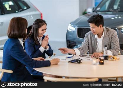 Asian customer giving the credit card to sales representative for purchase new car after sign contract and agreement in the showroom, Customer service and sales car concept
