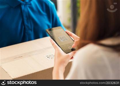 Asian customer young woman using mobile smartphone with QR code payment to receive parcel post box from delivery man, Hands of female scanning at door front house, Online shopping service concepts