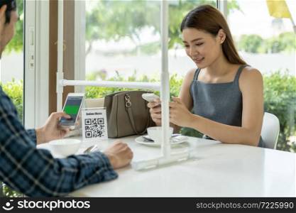 Asian customers scan QR code online menu. Customers sat on social distancing table for new normal lifestyle in restaurant after coronavirus covid-19 pandemic.