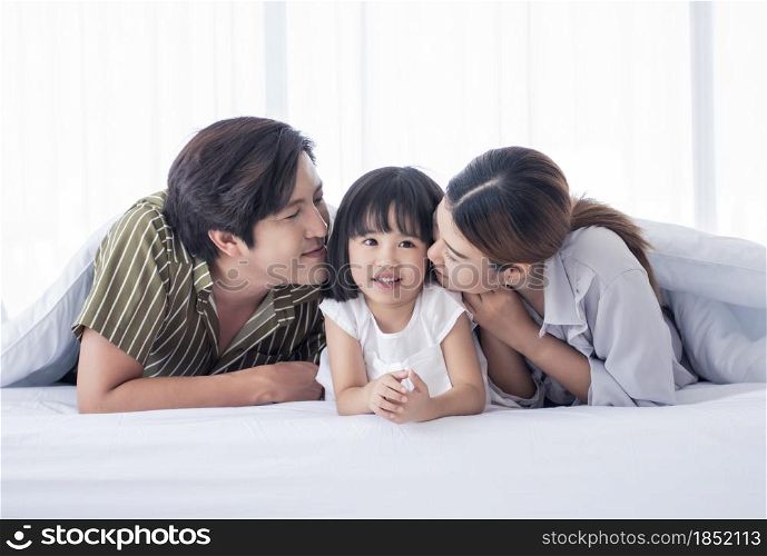 Asian cute family spending happy time on holidays and playing together at home on their white bed