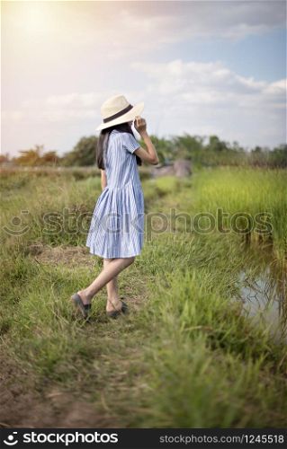 Asian cute girl with hat in green field and blue sky background. girl with hat in green field