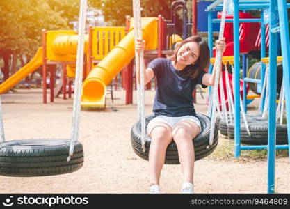 Asian cute teen happy smile sitting at swing kid playground park, leisure young innocent girl.