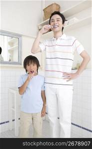 Asian dad and son brushing their teeth