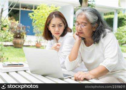 Asian daughter teaching old elderly woman use online Social media in computer laptop after retirement. Concept of Learning technology and adaptation of the elderly