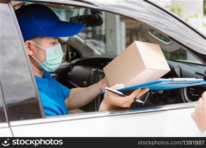 Asian delivery courier young man driver inside van car giving parcel post boxes to customer receiving both protective face mask, under curfew quarantine pandemic coronavirus COVID-19
