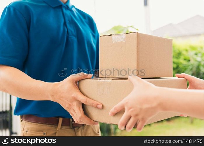 Asian delivery express courier young man giving boxes to woman customer receiving both protective face mask, under curfew quarantine pandemic coronavirus COVID-19