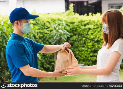 Asian delivery express courier young man giving paper bags fast food to woman customer receiving both protective face mask, under curfew quarantine pandemic coronavirus COVID-19