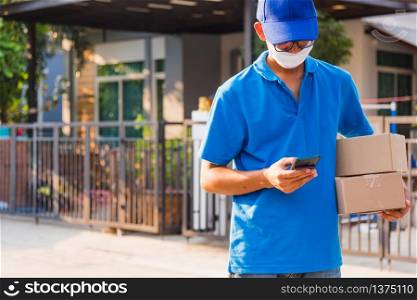 Asian delivery man courier online holding deliveries out boxes and using mobile phone contact the customer he protective face mask service under curfew quarantine pandemic coronavirus COVID-19