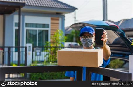 Asian delivery man courier Place deliveries boxes at home and showing mobile phone blank screen for customer sign he protective face mask service under curfew quarantine pandemic coronavirus COVID-19
