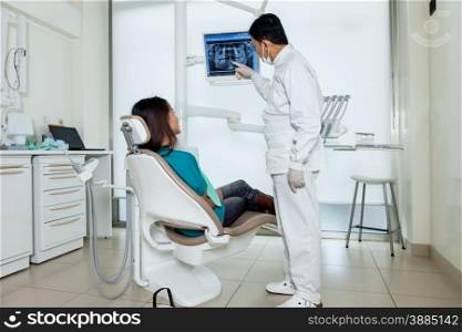 Asian dentist is showing X-ray on a screen to his patient