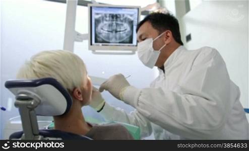 Asian dentist visiting young woman in dental studio, people and oral hygiene, health care in clinic, x-rays on computer screen. 9of19