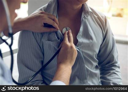 Asian doctor is using a stethoscope listen to the heartbeat of the elderly patient.