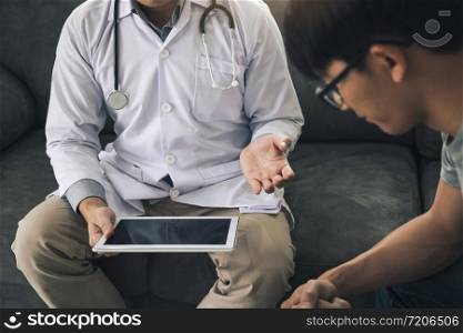 Asian doctor visited the patient at home while using the tablet explaining the patient condition and the treatment result.