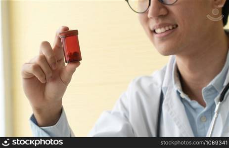 Asian doctor with stethoscope and uniform holding a medicine bottle And is explaining the medicinal properties of the patients. Concept of Medical consultant And medical services
