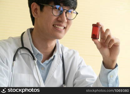 Asian doctor with stethoscope and uniform holding a medicine bottle And is explaining the medicinal properties of the patients. Concept of Medical consultant And medical services