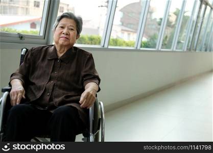 asian elder woman in wheelchair resting near window. elderly female relaxing at home. senior leisure lifestyle