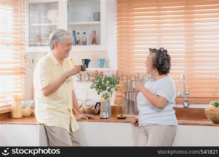 Asian elderly couple drinking warm coffee and talking together in kitchen at home. Chinese couple enjoy love moment while taking together at home. Lifestyle senior family at home concept.