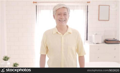 Asian elderly man feeling happy smiling and looking to camera while relax on the sofa in living room at home. Lifestyle senior men at home concept.