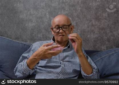 Asian elderly man takes his medicine, showing that taking care of his healthcare.