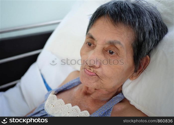 Asian elderly woman lay sick on bed,concept of post-retirement health.
