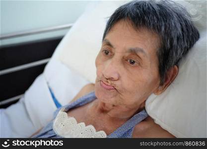Asian elderly woman lay sick on bed,concept of post-retirement health.