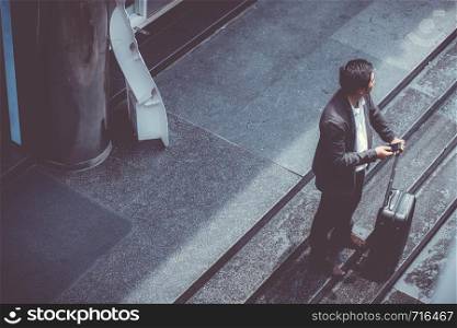 Asian elegant businessman wear suit talking mobile phone while walking holding suitcase outdoor on street, young man contact with customer appointment, communication business concept.