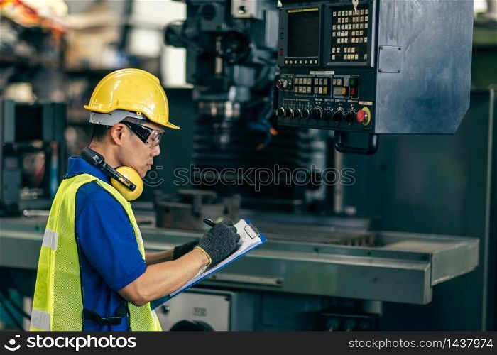 Asian engineer checking the machine in factory, worker writing note with list paper.