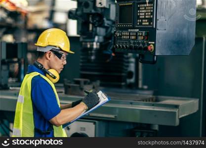 Asian engineer checking the machine in factory, worker writing note with list paper.