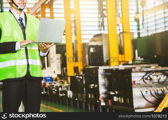 Asian engineer factory inspection with man business engineer hold computer with robot ai machine assist production in industry we wears a helmet female working metalwork control in industrial