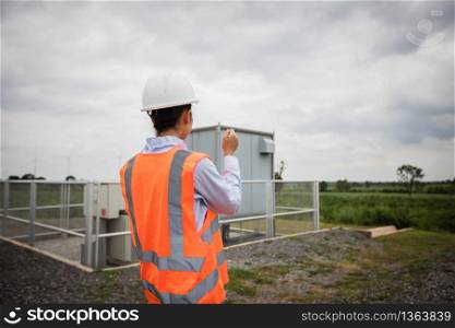 Asian engineer with hardhat using tablet pc computer inspecting and working at wind turbine farm Power Generator Station