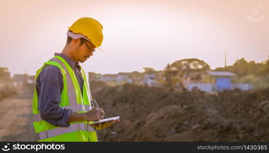 Asian engineer with hardhat using tablet pc computer inspecting and working at construction site